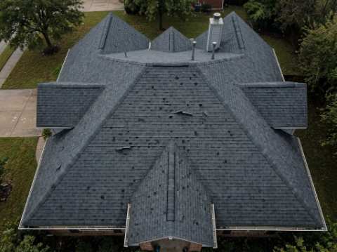 Storm-damaged residential roof photographed from above